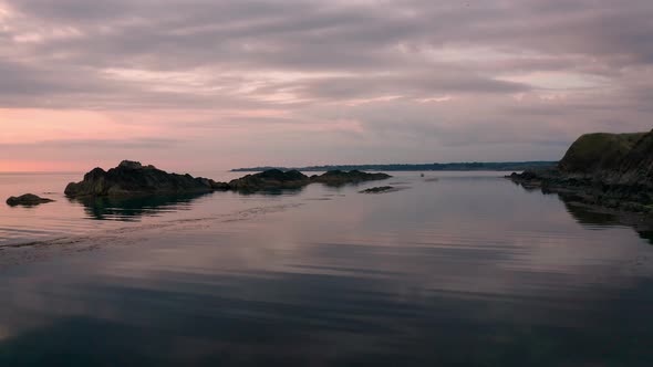 Drone flight around a picturesque rocky coastline and small fishing boat