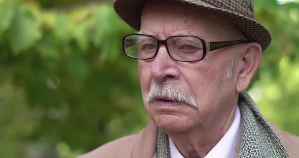 Portrait of Lonely, Thoughtful Senior Man Looking Into Camera in Park