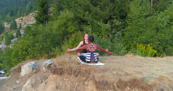 Friends performing yoga on top of a mountain 4k