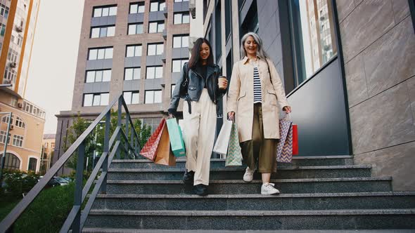 Asian Mother and Adult Daughter Smiling Talking Carrying Shopping Bags and Coffee in Paper Cup