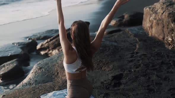 Backside View Girl Doing Yoga Stretching on Mat Black Sand Beach Near Ocean