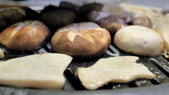 The Cook Prepares Mushrooms on Korean BBQ Gril Plate