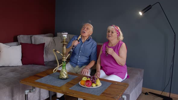 Elderly Couple Smoking Hookah at Home. Senior Grandmother and Grandfather Having Fun, Relaxing