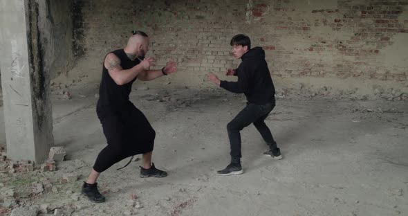Skilful Fighting of Two Angry Men in Black Clothes in an Abandoned Building