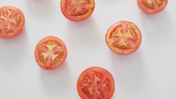 Video of fresh halved red tomatoes on white background