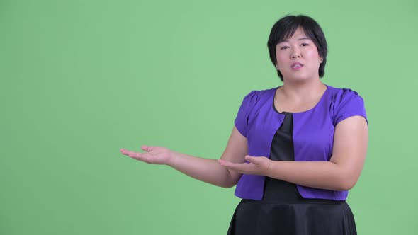 Happy Young Overweight Asian Woman Presenting Something