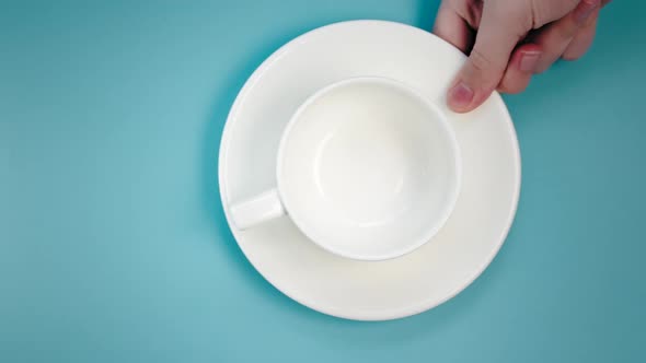 Woman Puts Cup with Saucer on Table