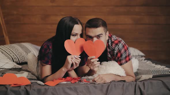 Adult man and woman in plaid shirts are lying on the bed