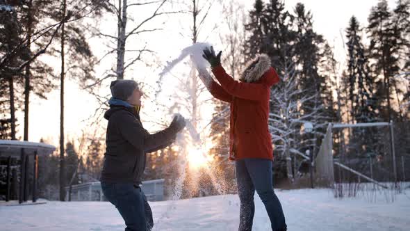 Young Couple Throwing Snow Particles in the Air