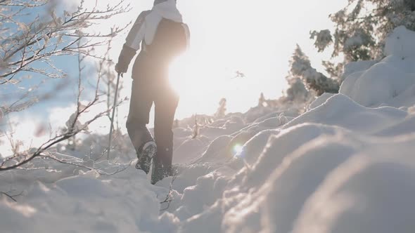 A Young Woman is Climbing a Snowcovered Road Up a Mountain