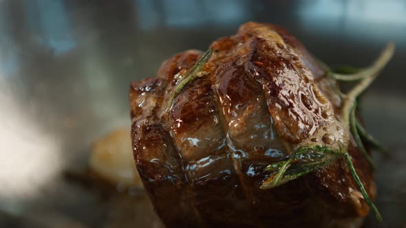 Close-up: Chef pouring sauce over filet mignon while cooking