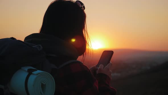 Silhouette of Young Tourist Woman Use Phone with Dramatic Sunset Sky Background. Always Connected