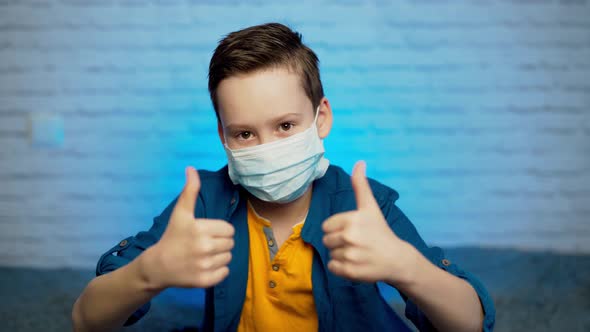 Child showing thumb up wearing protective face mask