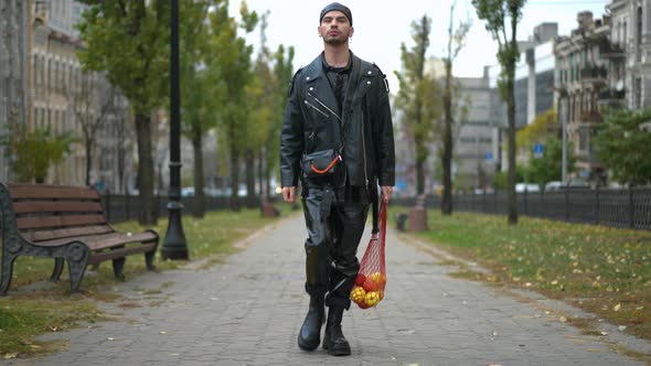 Wide Shot Portrait of Young Confident Gay Man Walking with Shopping Net in Urban City Looking Around