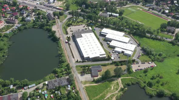 Aerial Shot of Truck with Attached Semi Trailer Leaving Industrial Warehouse/ Storage Building/ Load