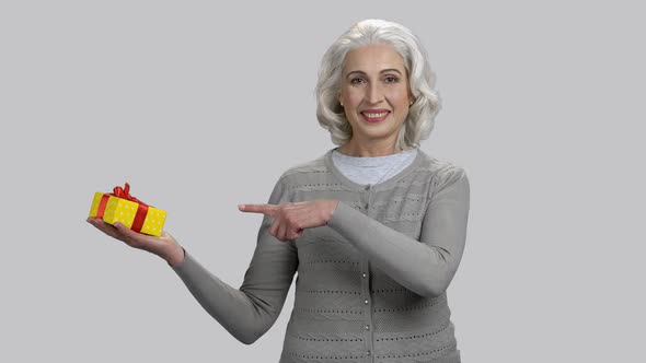 Old Retired Woman Pointing at Gift Box