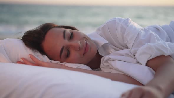 Closeup Portrait of Happy Rested Young Woman Opening Eyes Waking Up Smiling with Blurred Blue Sea