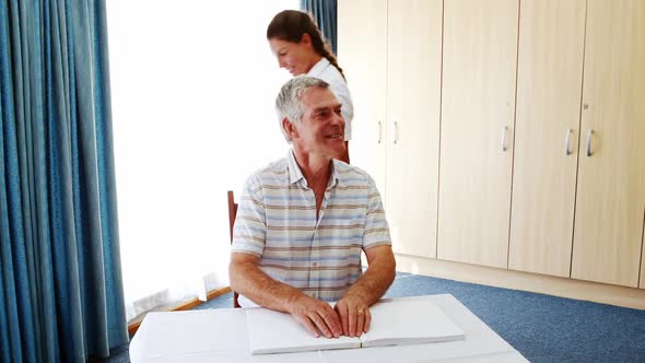 Senior man is reading beside a nurse