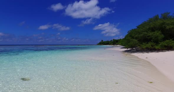 Wide flying island view of a white sandy paradise beach and blue ocean background in colourful 4K