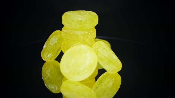 Pile Of Sweet Lemon Candies Rotating With Reflection On Glass Black Surface. - Close Up, Macro Shot