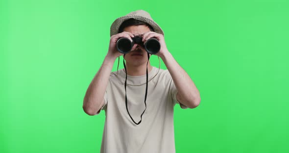 Young Man Explorer in Hat Looking Through Binoculars
