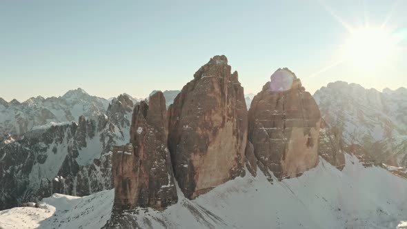 Circling drone shots of Tre Cime mountain face the dolomites backlit