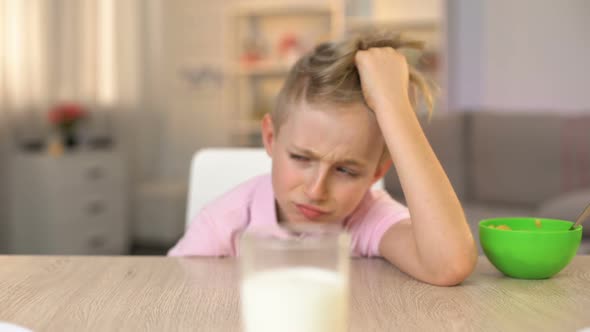 Capricious Male Kid Looking Sadly Glass of Milk on Kitchen Table, Healthy Meal