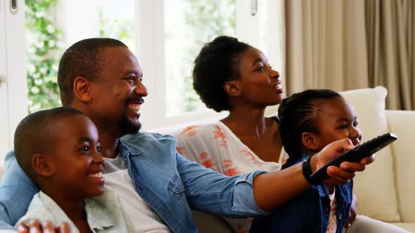 Parents and kids having fun while watching television in living room