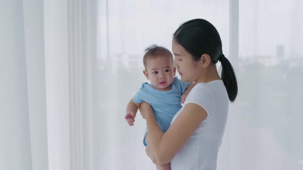 Family concept. Asian mom is holding a baby in the house