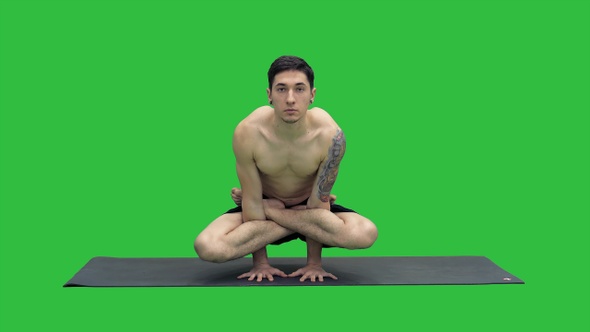 Practicing Yoga exercises Scale Pose - Tolasana on a Green
