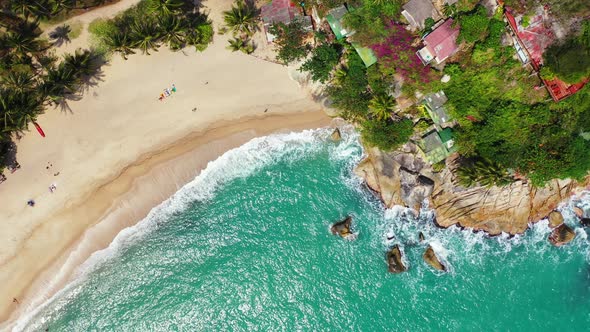 tropical beach background, White sandy beach, palm trees and bungalows on the hill. Waves washing th