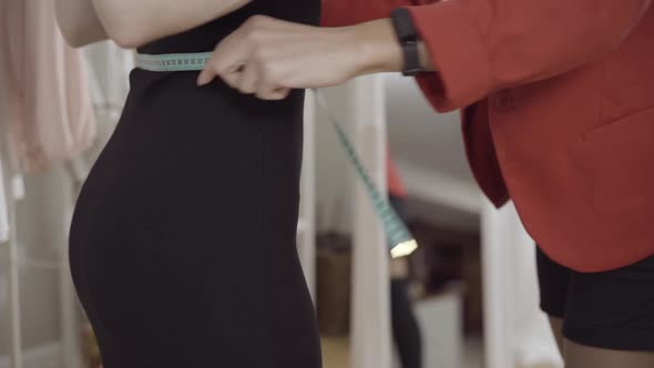 Unrecognizable Female Tailor Using Measuring Tape for Waist Measurement