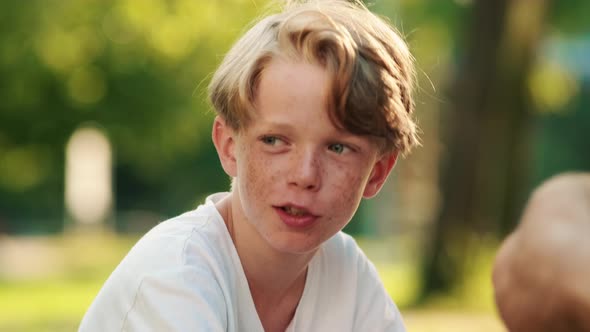 A close-up view of a little boy is talking while having a picnic on the grass