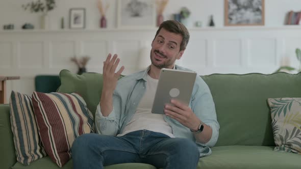 Young Man Talking on Video Call on Tablet on Sofa