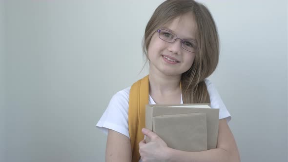 Portrait of Pretty Cute Smiling School Girl in Glasses with Books