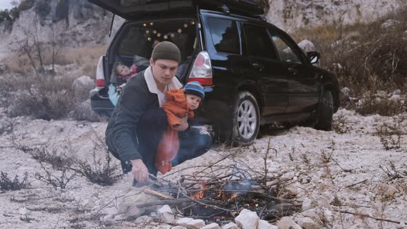 Traveler with family makes a bonfire the background of an open black car