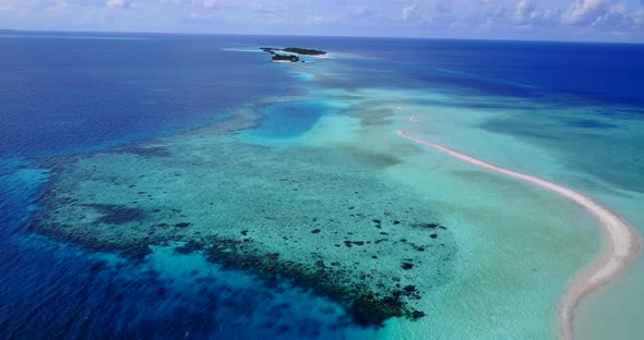 Wide flying copy space shot of a white sandy paradise beach and aqua blue water background in hi res