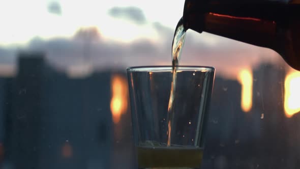Beer is poured into a short glass against a defocused window
