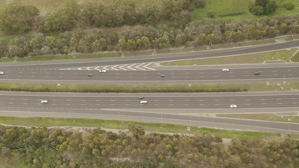 Aerial perspective of modern highway as vehicles travel back and forward during day light hours.