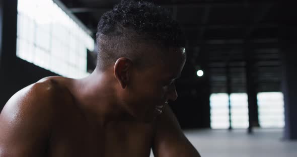 Portrait of african american man resting after battling ropes in an empty urban building