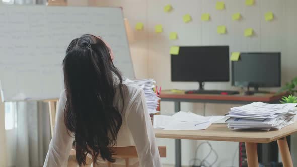 Back View Of Asian Woman Leaning On The Chair And Sleeping While Working Hard With Documents