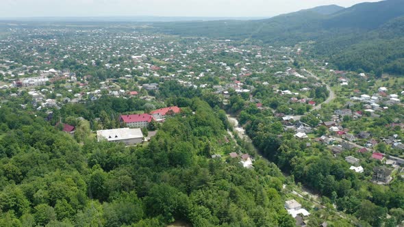 Aerial Drone View of Red Roofs Among Green Trees in a Mountain Valley Township