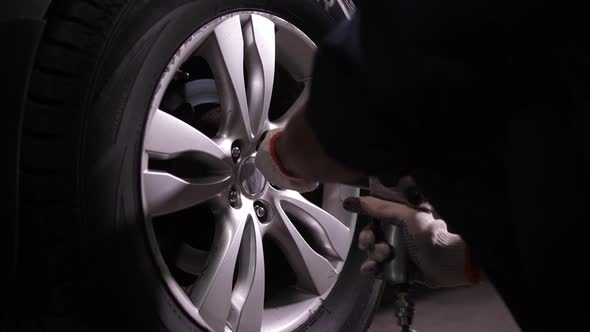 Worker of Car Repair Service Unscrewing Wheel