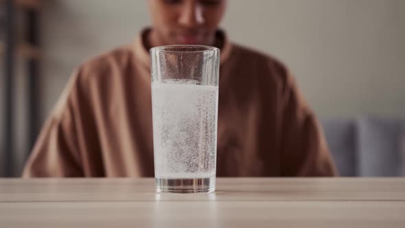 Woman Sits Behind Glass of Water with Gas From of Effervescent Powder or Tablet