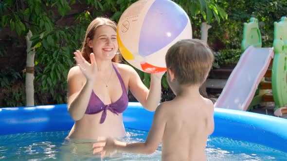 Cute Little Boy Playing in Inflatable Swimming Pool with Colorful Beach Ball