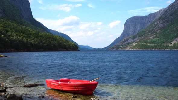 Tourist boat at the fjord shore in Norway with mountains in the background.