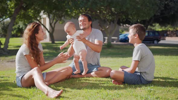 Family Walk with Baby Toddler Making First Steps on Park Grass Happy Family Play Together on Nature