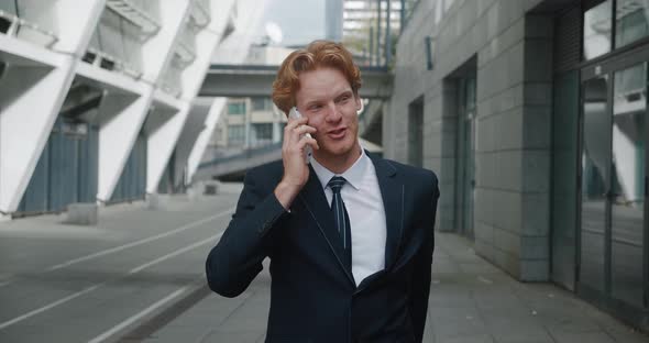 Smiling Handsome Businessman in Formal Suit Emotionally Talking By Mobile Phone While Standing