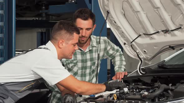 Car Service Mechanic Repairing Automobile While Talking To the Customer