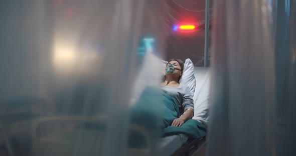 Sick Aged Woman with Oxygen Mask Coughing Lying in Quarantine Ward at Hospital